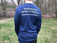 A young man wearing a long sleeve polyester t-shirt that's navy blue. The writing across the shoulder blades reads "Breaking Down Barriers to Adventure" in lime green. Underneath reads www.waypointadventure.org